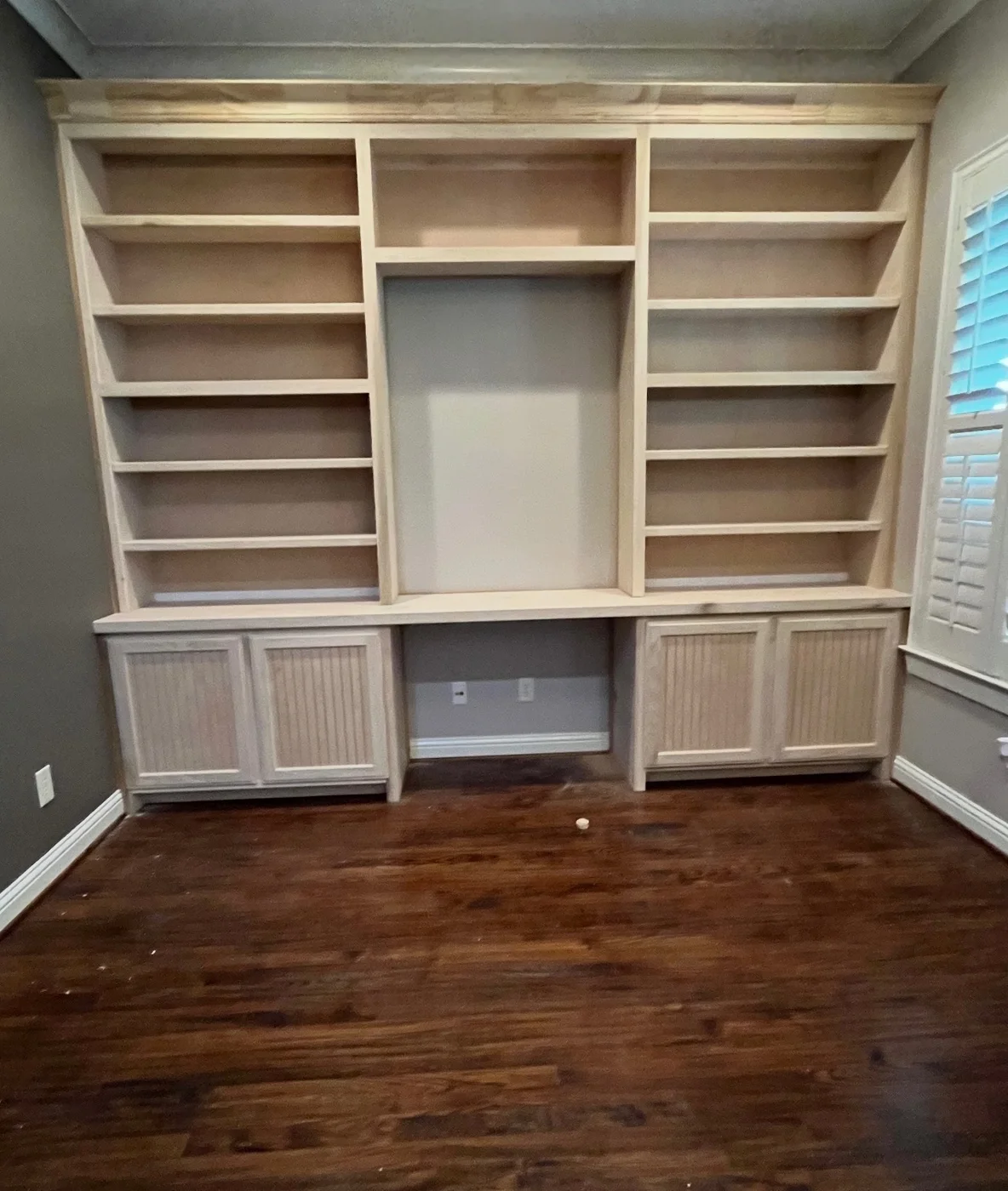 Wall-to-wall media built-in with open shelves and base cabinets