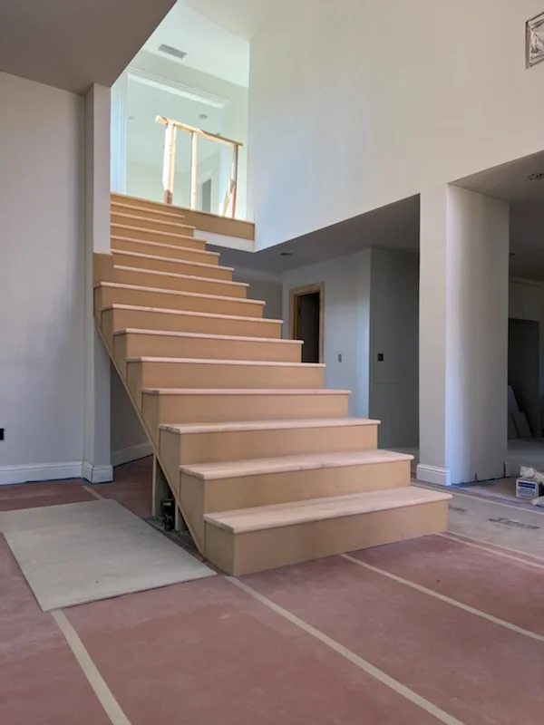 Unfinished wood staircase rising through an open interior